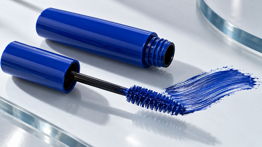Open tube of vivid blue mascara with an unbranded wand on a clean cosmetic surface