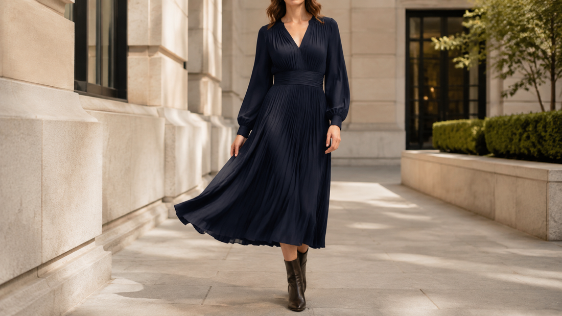 Woman wearing a flowing navy midi dress with ankle boots in a sunlit city courtyard
