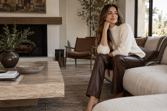 Adult woman wearing brown leather pants with a cream knit top